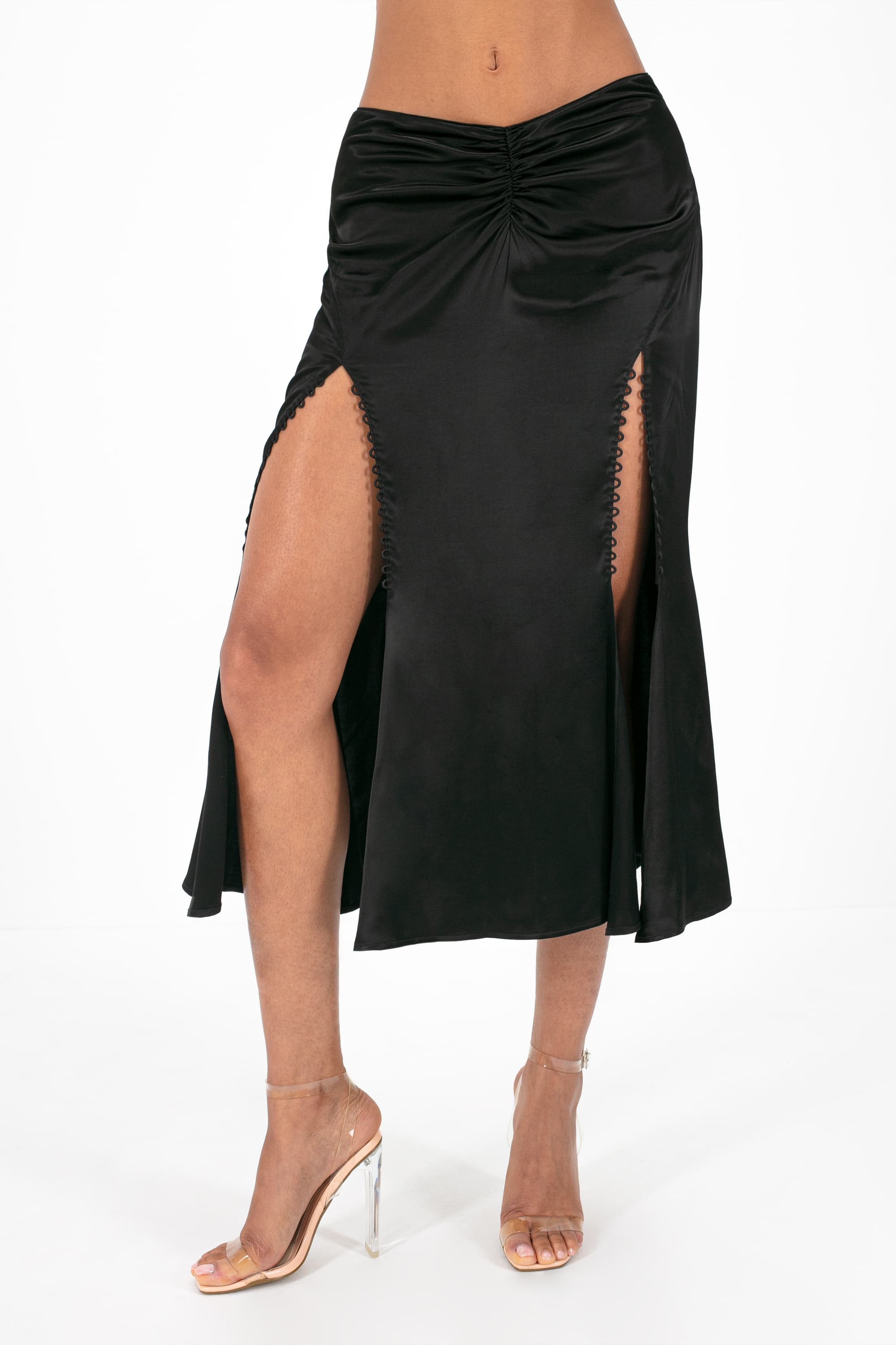 Woman wearing black Andromeda skirt standing against white background, front view, lower body